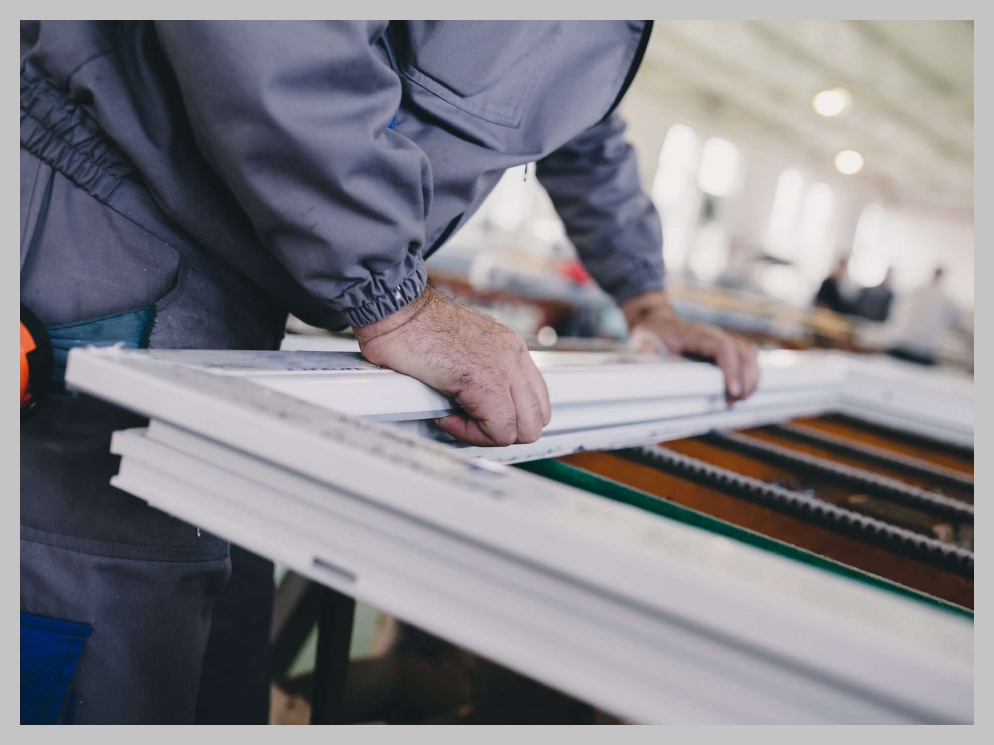 Worker assembling a window frame in a factory setting.