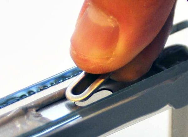 A person is using a small metal tool to cut the wire.
